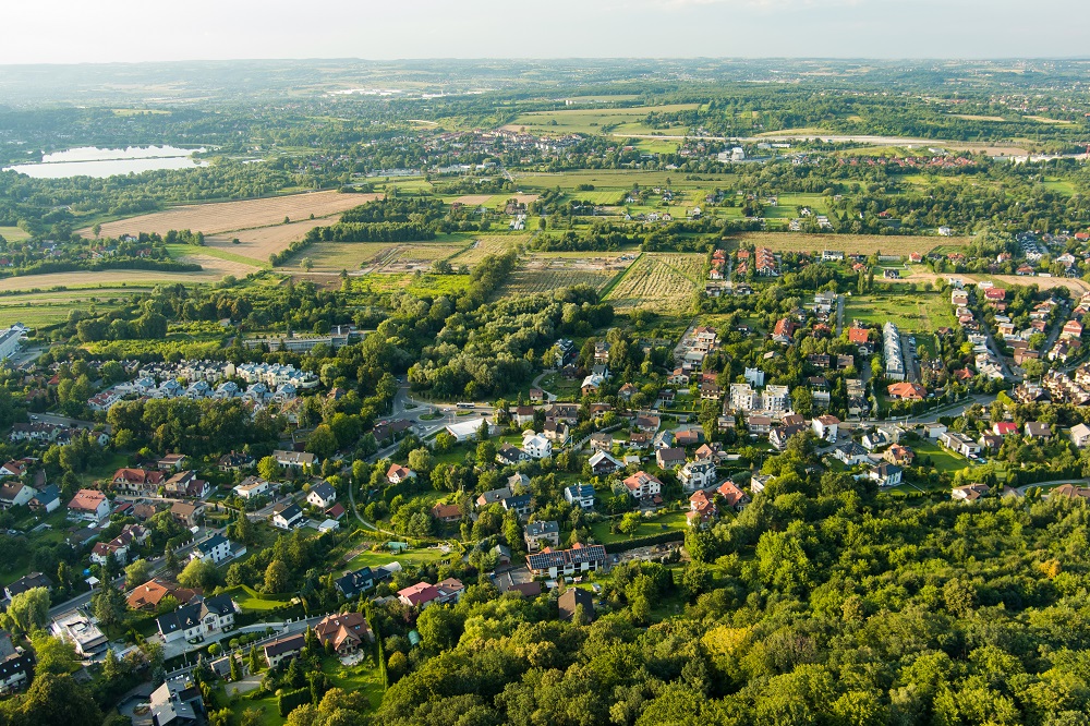 Widok z góry na zielone przedmieścia, z zabudową jednorodzinną i dużą ilością drzew