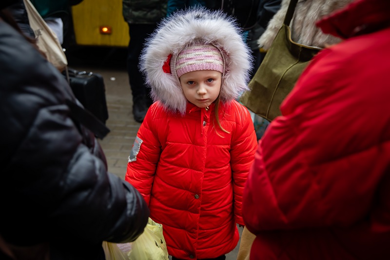 Kilkuletnia dziewczynka w ciepłej kurtce, poważnie patrząca w obiektyw aparatu