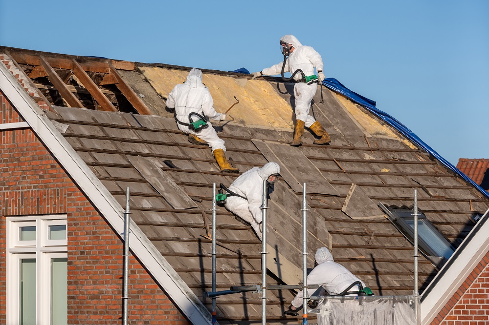 Profesjonalna ekipa w odzieży ochronnej usuwa dach z eternitu